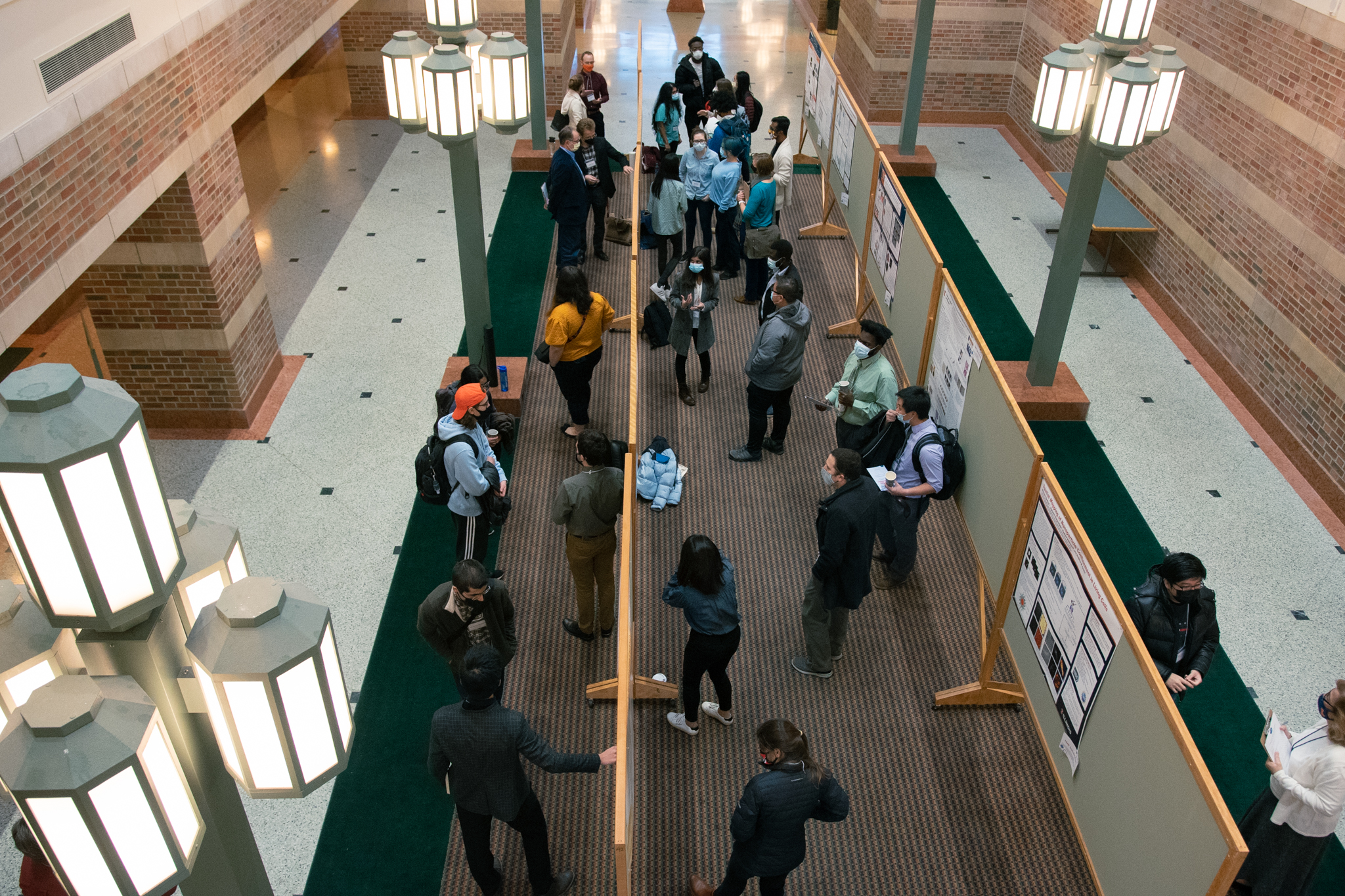 Wide shot of a graduate student poster session - students standing around looking at posters.
